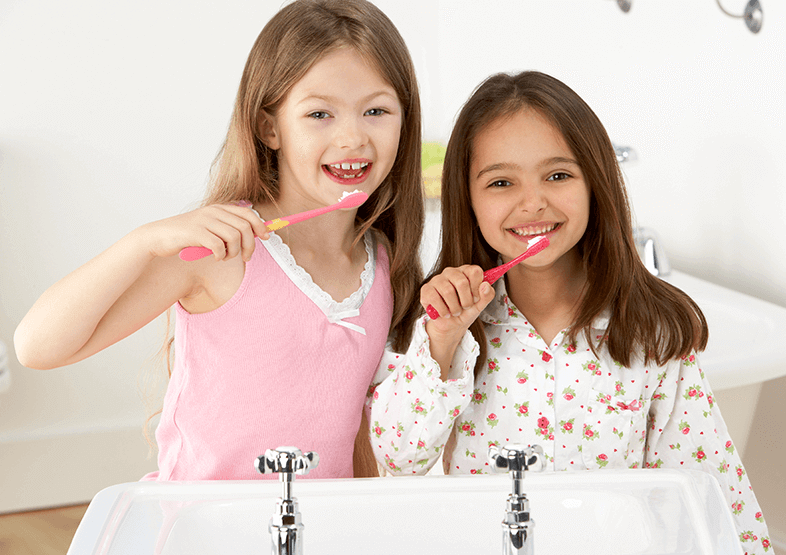 young girls brushing their teeth