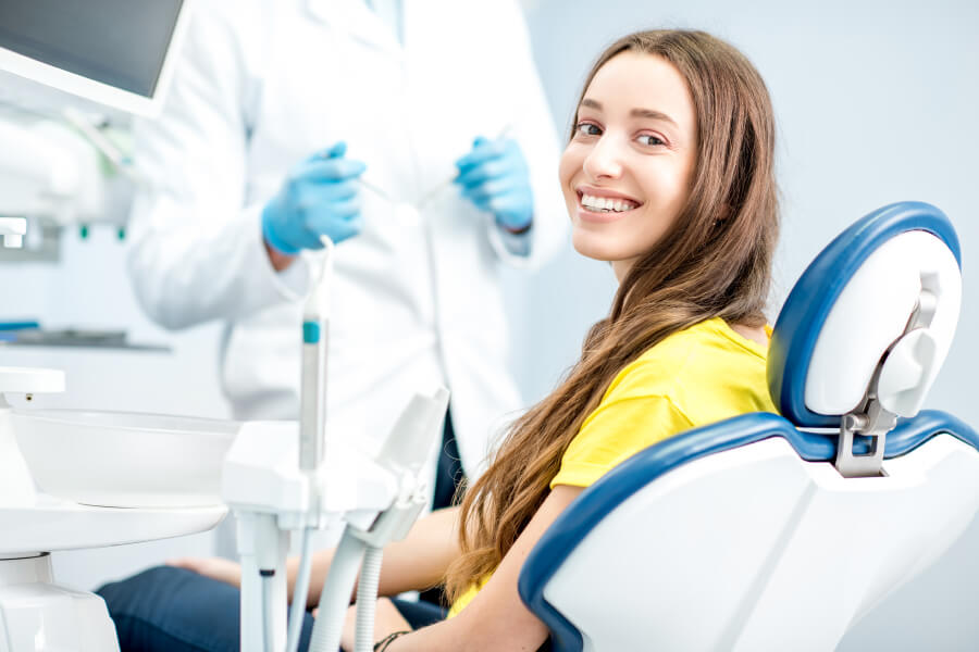 Brunette woman smiles while sitting in a dental chair at Abidin and Can, DDS awaiting her biannual dental cleaning