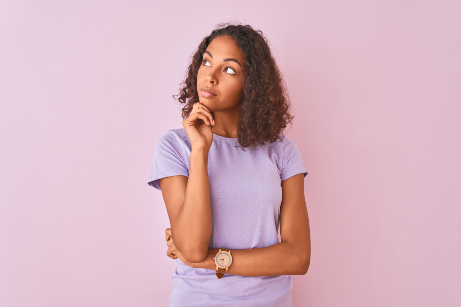 Brunette woman in a lavender shirt wonders when teeth whitening isn't recommended