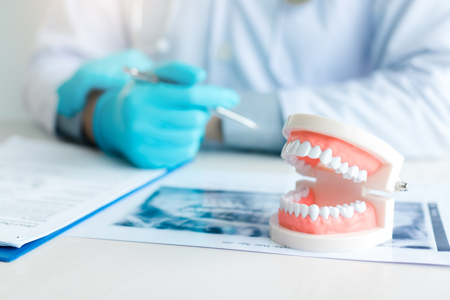 Cosmetic dentist sitting at a desk with a mouth model for a cosmetic dentistry consultation with a patient
