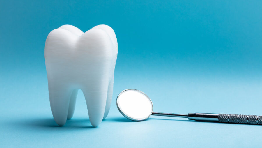 A white tooth next to a special dental mirror against a blue background at the dentist in Westerville, OH