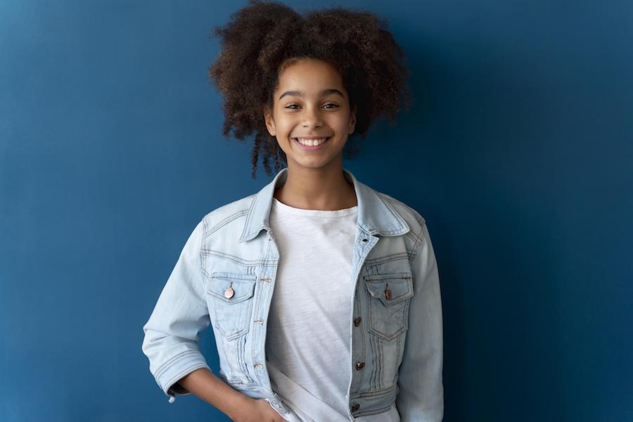 Black teen with curly hair smiling.