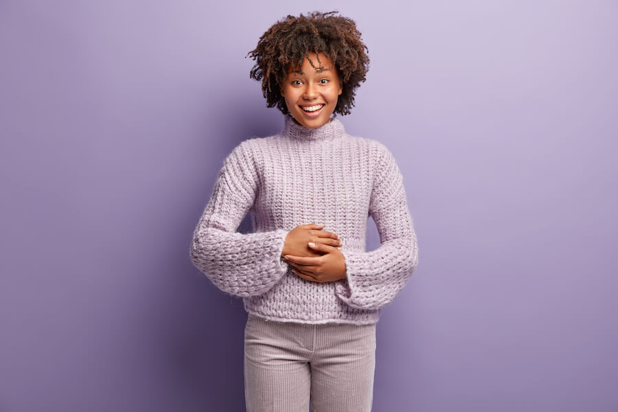 gut health, oral microbiome, smiling Black woman with hands on belly